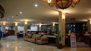 Eine Hotelhalle mit einer Rezeption, Sofas und einem Kronleuchter.