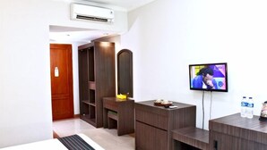 Ein Hotelzimmer mit Holzschrank, Spiegel, Fernseher und Schuhablage.