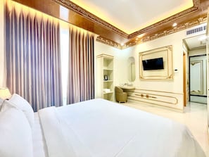 Una habitación de hotel con una cama grande, televisor, espejo y armario.