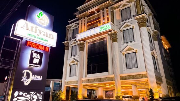 Ein mehrstöckiges Hotel im klassischen Stil, mit einem markanten Eingang und beleuchteter Beschilderung.