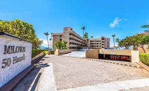 A parking area with a building labeled "MILOWAI 50 HAUKI" in the background. - Turtles, Whales & Waves from Oceanfront Private Lanai (Wailuku)