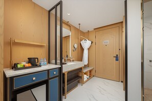 A modern bathroom with a wooden vanity, a large mirror, a towel rack, and a shower area.