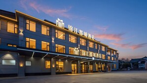 Ein Hotel mit moderner Fassade, zahlreichen Fenstern und beleuchteter Beschilderung.