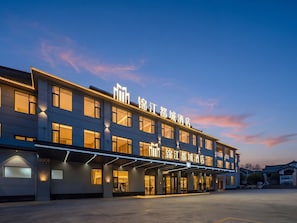 Un hotel amb façana moderna, moltes finestres i senyalització il·luminada.
