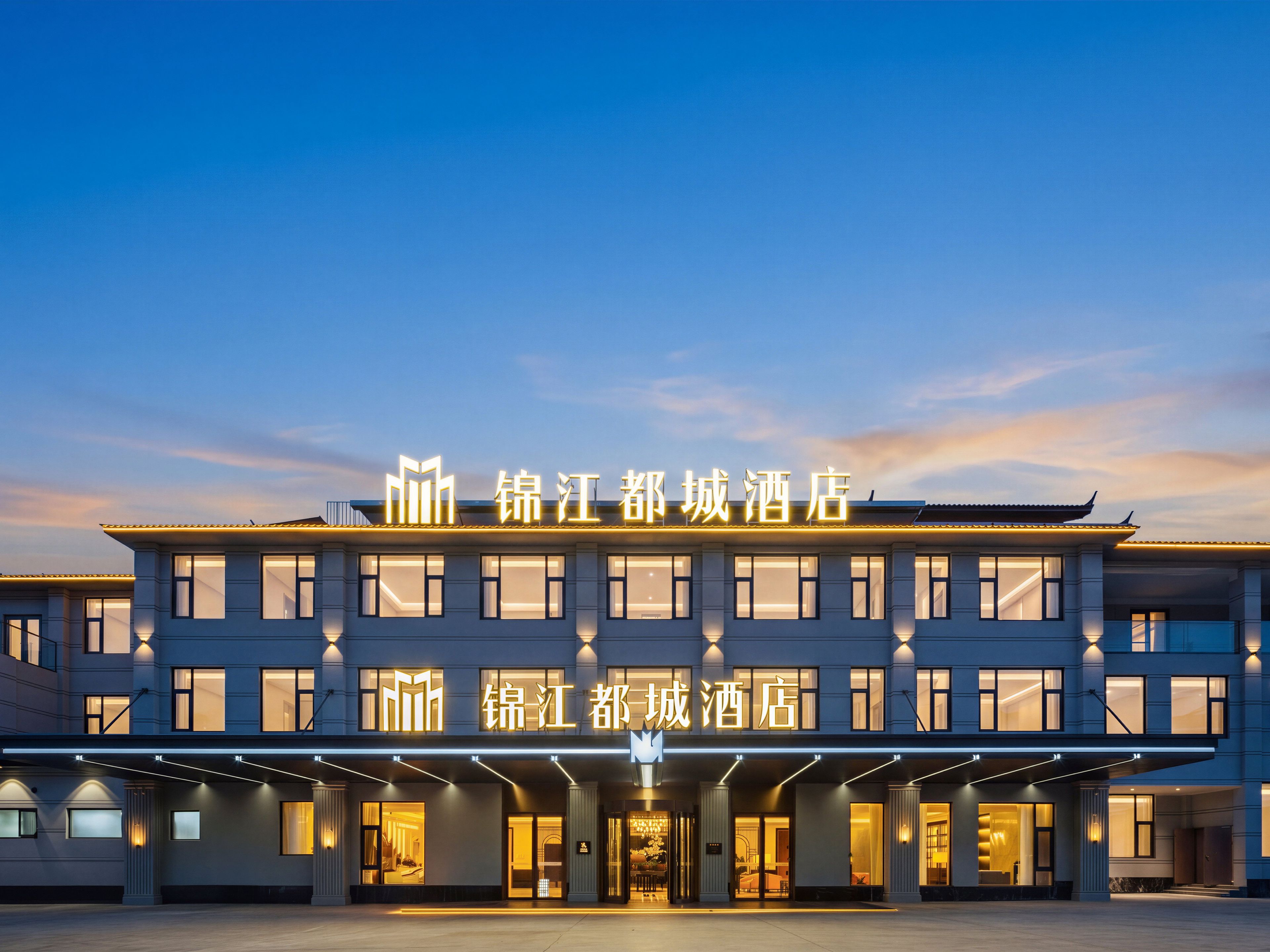 A hotel with a modern facade, illuminated signage, and a spacious entrance area.