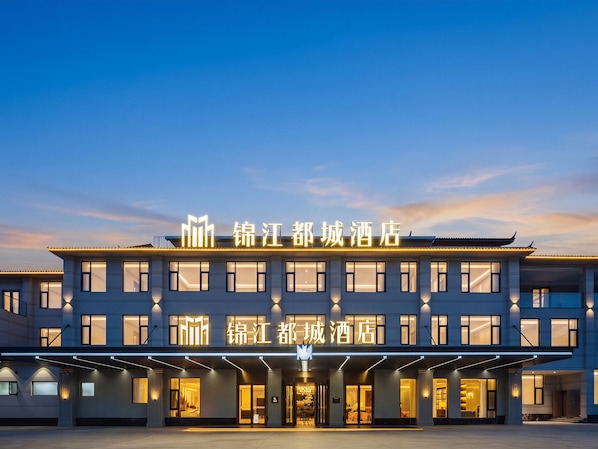 A hotel with a modern facade, illuminated signage, and a spacious entrance area.