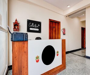 A reception desk with a company service sign, a fire extinguisher, and a door with the number 201. - Deluxe Room Collection O Sadar Bazaar (Gurugram)