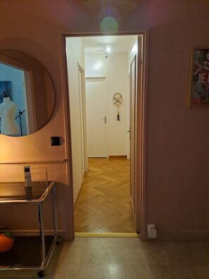 Ein Flur mit einer Tür am Ende, die zu einem Zimmer mit Deckenventilator führt.