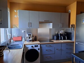 Eine moderne Küche mit grauen Schränken, Edelstahlgeräten und einem eingebauten Backofen.