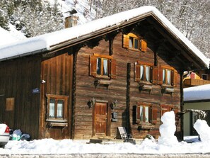 Eine Holzhütte mit zahlreichen Fenstern und einem mit Schnee bedeckten Dach.