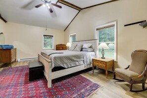 Een slaapkamer met een bed, een stoel, een nachtkastje, een dressoir en een raam.