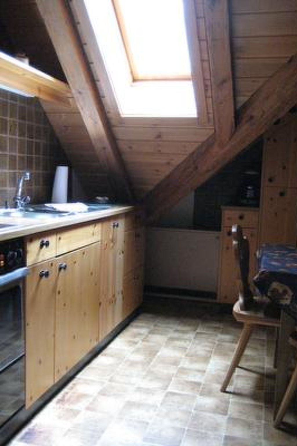 A small kitchen with wooden cabinets, a tiled floor, and a skylight.