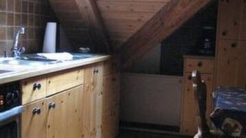 A small kitchen with wooden cabinets, a tiled floor, and a skylight.