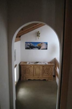A hallway with a wooden bench, a wall-mounted light fixture, and a framed picture.