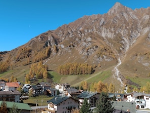 A mountain village with traditional buildings, a winding road, and a prominent mountain in the background.