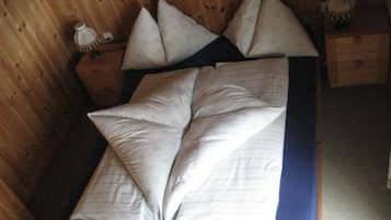 Een houten bed met een blauwe matrasbeschermer en meerdere kussens.