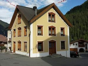 Ein zweistöckiges Gebäude mit vielen Fenstern und einem geneigten Dach in einer gebirgigen Gegend.