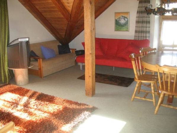 Ein gemütliches Wohnzimmer mit einem roten Sofa, einem Holzesstisch und Stühlen.