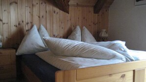 En træseng med sengegavl, puder og et natbord med en lampe.