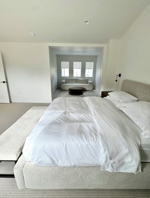 Ein modernes Schlafzimmer mit einem großen Bett, einer Couch und einer kleinen Sitzecke.