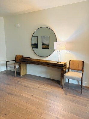 Ein Zimmer mit Holzboden, einem runden Wandbild, einem Schreibtisch mit Stuhl und einer Lampe.
