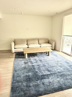 A living room with a beige sofa, a wooden coffee table, and a blue rug. - Awesome 5-bedroom townhome near Deer Valley (Heber City)