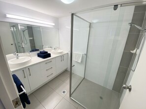A modern bathroom with two sinks, a glass shower enclosure, and a large mirror. - Gold Coast central, fabulous golf course resort, near beach, shops, restaurants (Clear Island Waters)