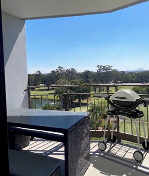 A balcony with a view of a golf course, a barbecue grill, and a table. - Gold Coast central, fabulous golf course resort, near beach, shops, restaurants (Clear Island Waters)