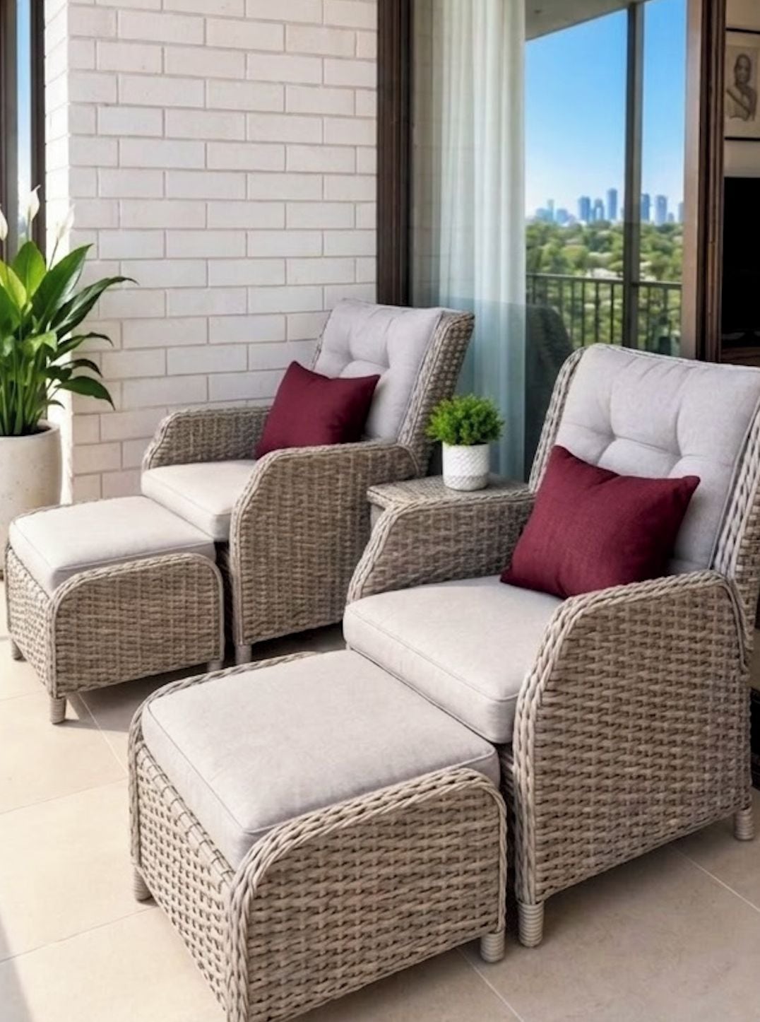 A wicker sofa set with cushions and a matching ottoman on a balcony with a city view.