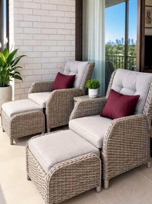 A wicker sofa set with cushions and a matching ottoman on a balcony with a city view. - Gold Coast central, fabulous golf course resort, near beach, shops, restaurants (Clear Island Waters)