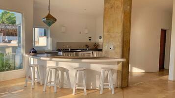 Una cucina moderna con una grande isola, sgabelli da bar e una lampada a sospensione.