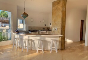 A modern kitchen with a large island, bar stools, and a hanging light fixture. - Private Villa Casa Limonaia Punta Zicatela (Puerto Escondido)