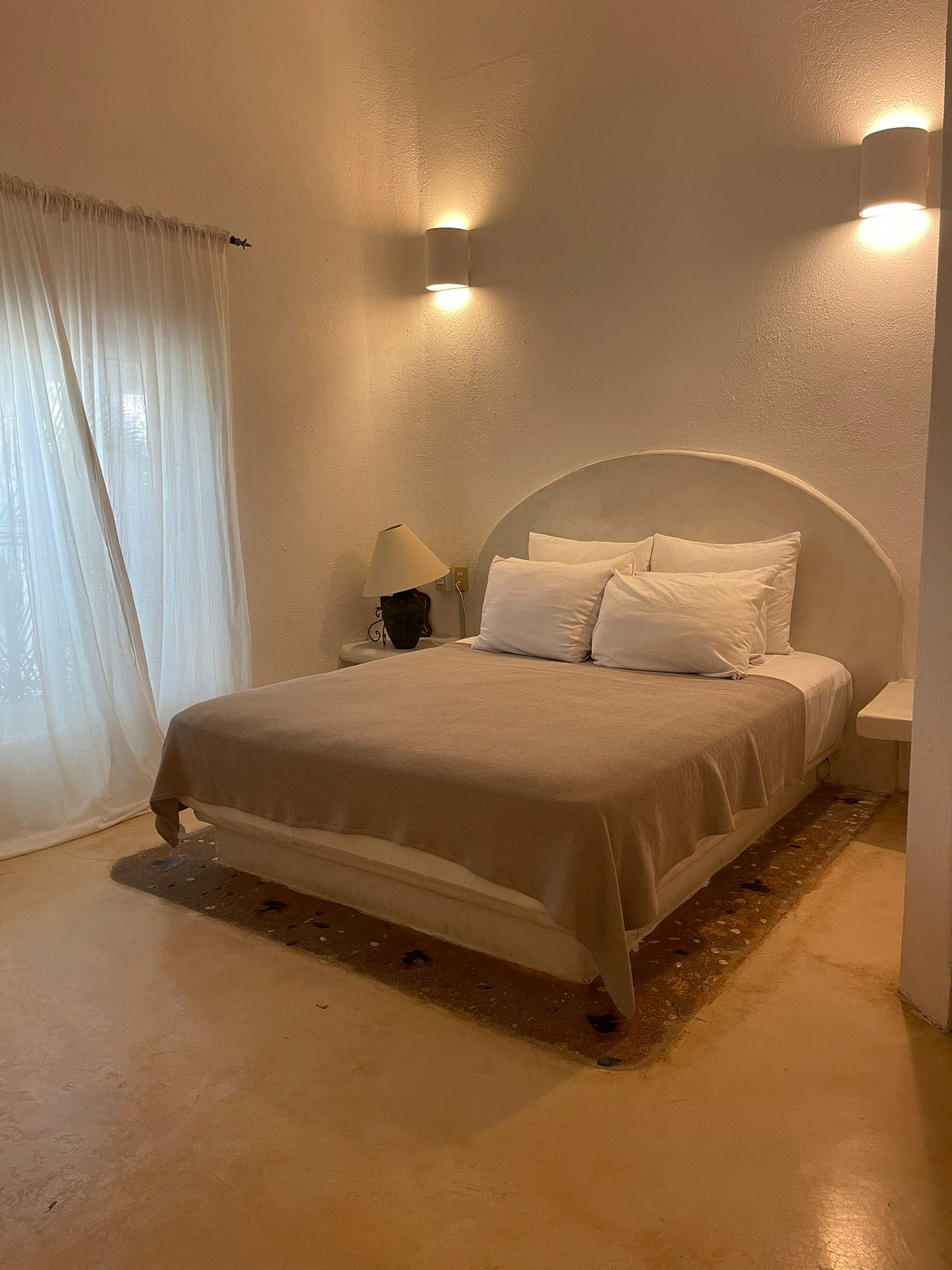 Una camera da letto con un letto, un comodino, una lampada e un punto luce a parete.