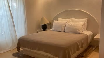 Una camera da letto con un letto, un comodino, una lampada e un punto luce a parete.