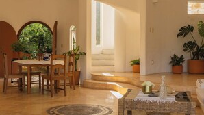 Uma sala espaçosa com mesa de jantar, cadeiras e escada que leva a um andar superior.