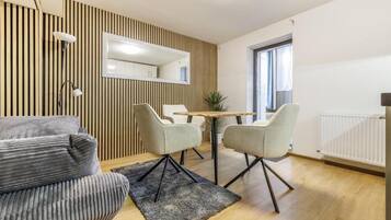 Una sala de estar moderna con un sofá, una mesa de comedor con sillas, un espejo y un radiador.