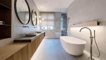 A modern bathroom with a freestanding bathtub, a large mirror, and a vanity with a sink.