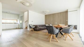 En moderne stue med spiseplads, sofa og køkken i baggrunden.