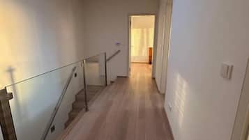 Un couloir doté d’une verrière, d’un plancher en bois et d’une rambarde en verre.