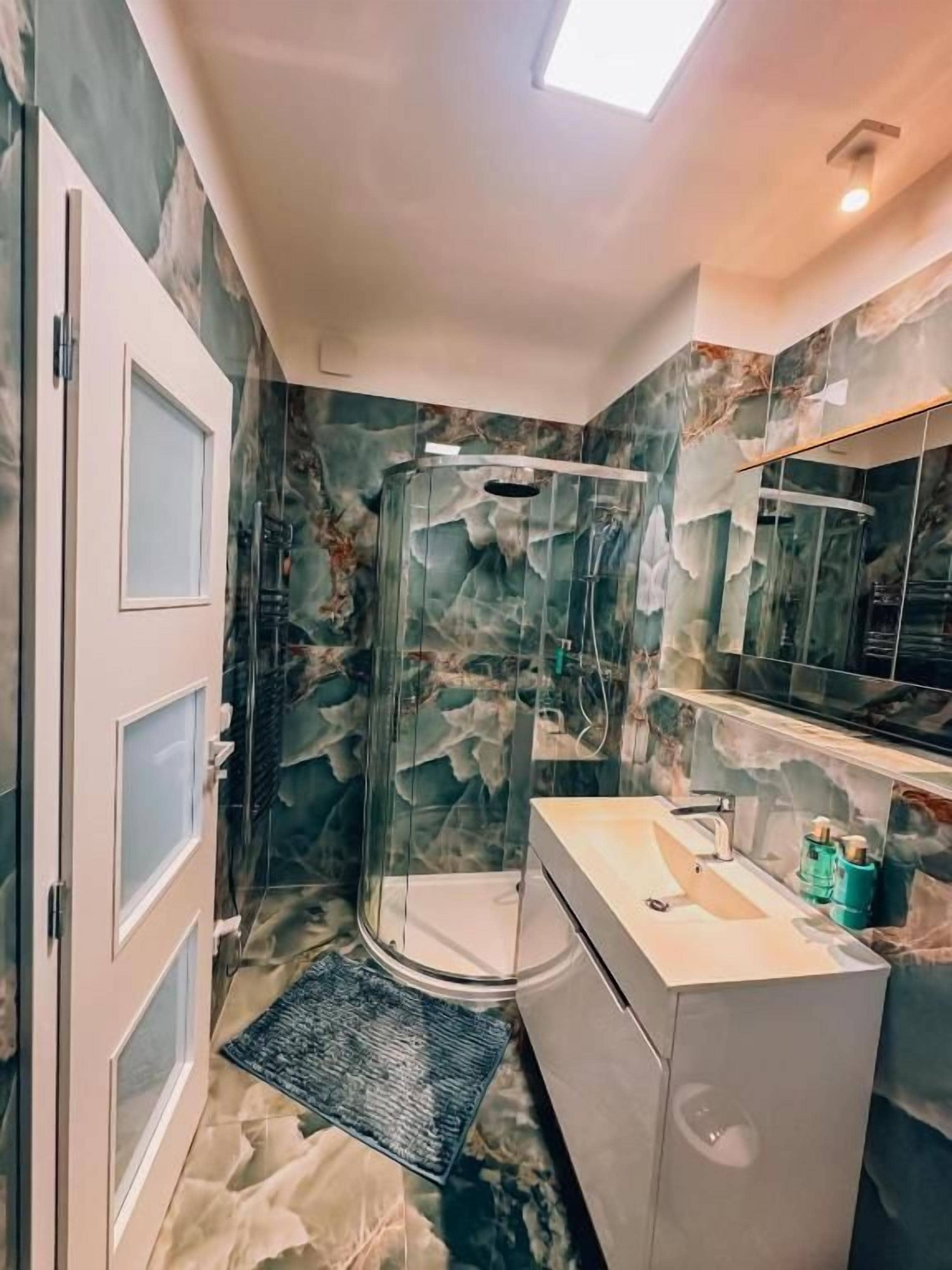 Un baño con cabina de ducha de vidrio, un lavabo y un espejo.