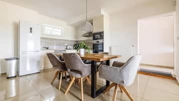 Una cocina moderna con una mesa de comedor, sillas y un refrigerador.