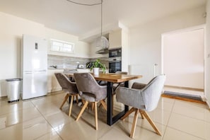 Cozinha moderna com mesa de jantar, cadeiras e frigorífico.