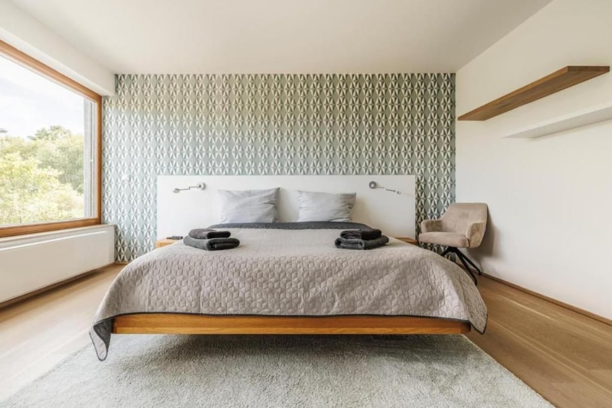 Quarto moderno com cama, cadeira e janela.