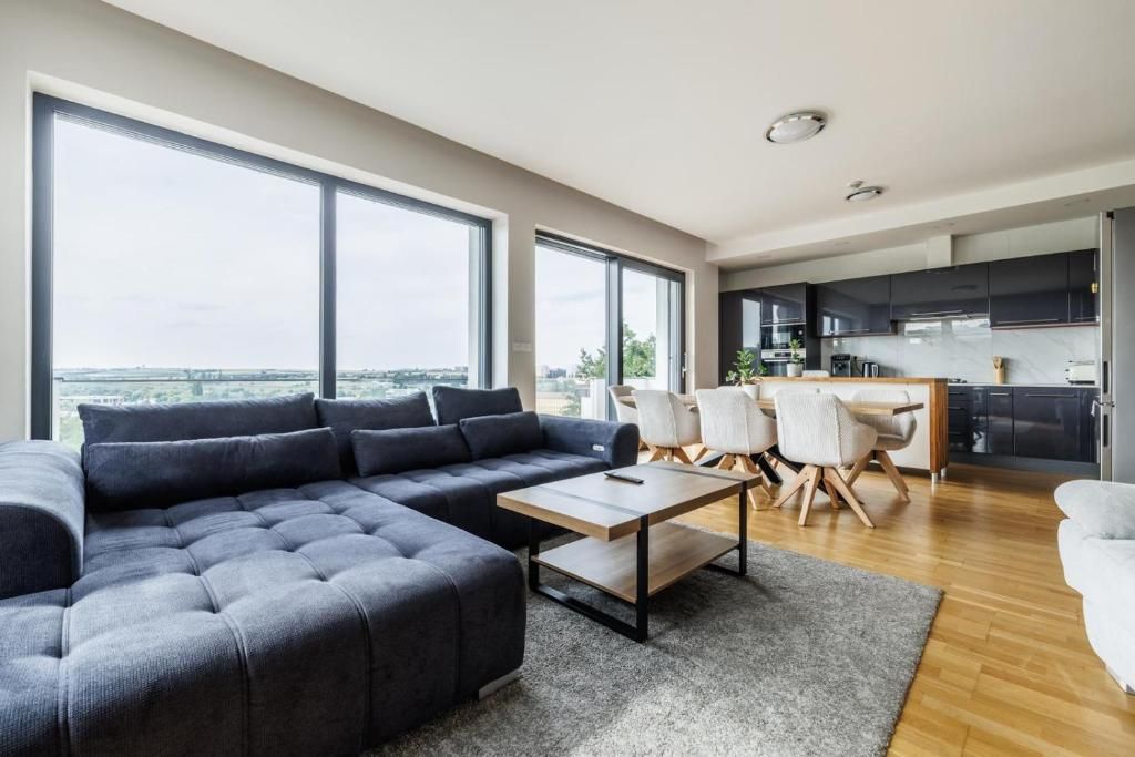 A modern living room with a sectional sofa, a coffee table, and a dining area with chairs.