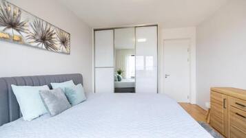 A bedroom with a bed, a wardrobe, a mirror, and a painting on the wall.