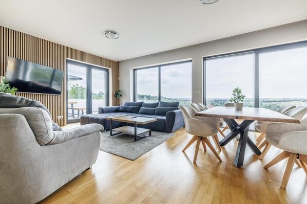 A modern living room with a sofa, a coffee table, and a dining table with chairs.