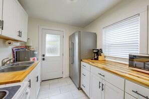 A compact kitchen with white cabinets, a stainless steel refrigerator, a coffee maker, and a window with blinds. - 2 Mi to Dtwn Savannah! WFH-Friendly Retreat (Savannah)