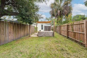 A backyard with a covered patio area, wooden fences, and a white building. - 2 Mi to Dtwn Savannah! WFH-Friendly Retreat (Savannah)