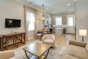 A modern living room with a flat-screen TV, wooden furniture, a dining area, and a kitchen with stainless steel appliances. - Brand-New Cottage Minutes to Lake Marion & Golf (Summerton)