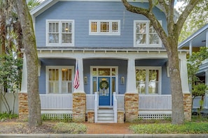 A two-story house with a blue exterior, white shutters, and a front porch with a brick column.
